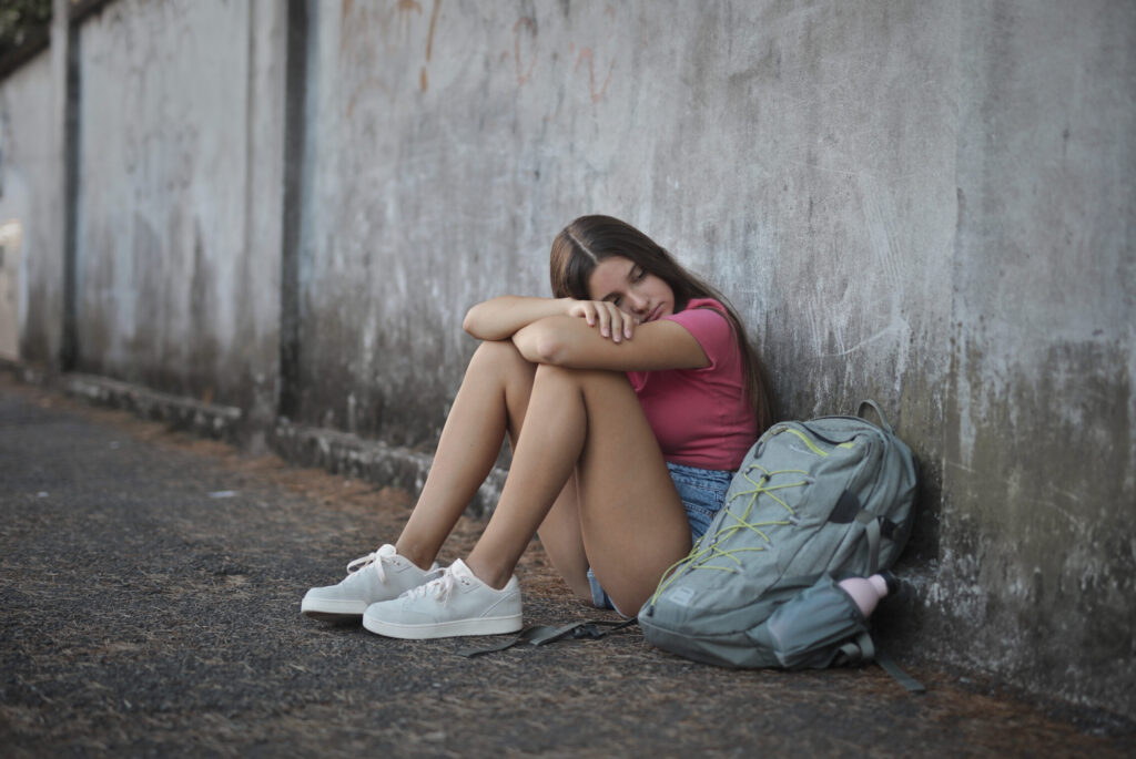 Sad and lonely girl leaning against a wall